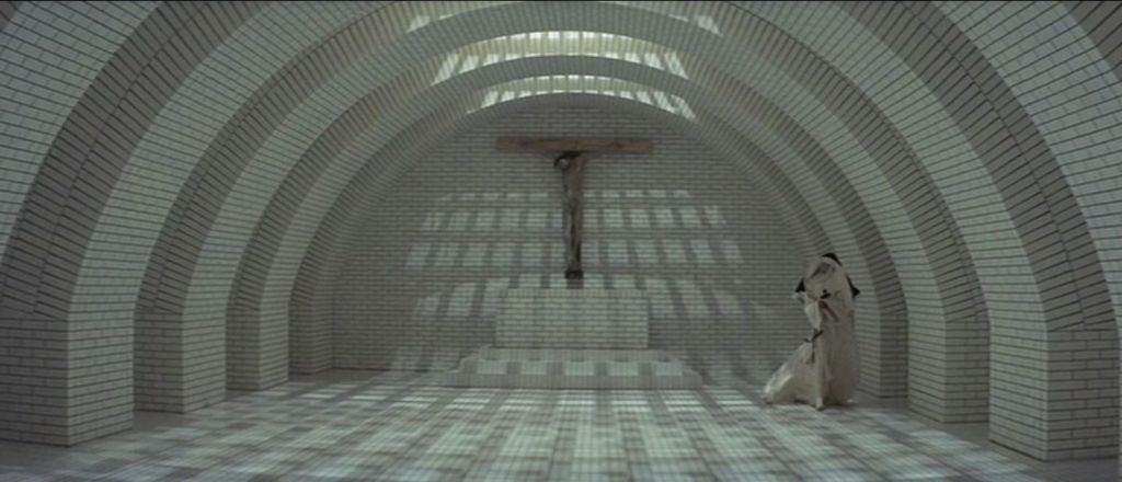 A cross at the end of a white brick room