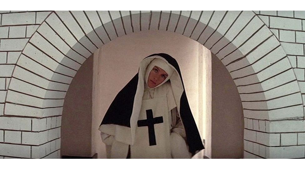 A disturbed nun passes under a entrance