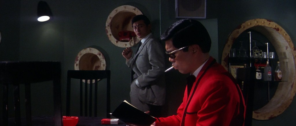 Man in red smokes while man in grey looks on